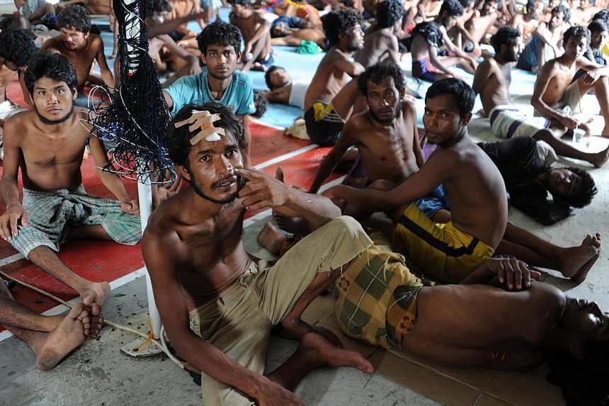 A group of rescued migrants, mostly Rohingya from Myanmar and Bangladesh, sit upon their arrival at the new confinement area in the fishing town of Kuala Langsa in Aceh province on May 15, 2015.&nbsp;-- PHOTO: AFP