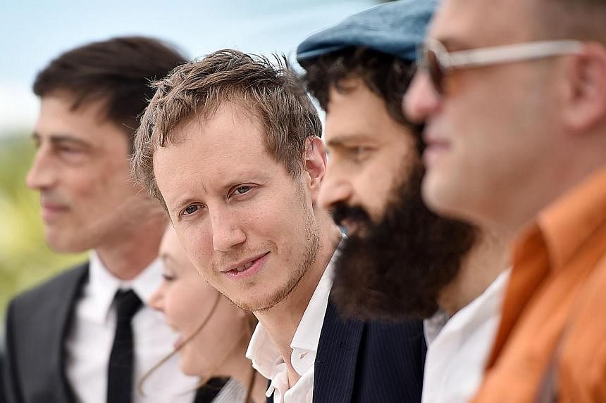 Hungarian director Laszlo Nemes (centre) poses with his cast during a photocall for the film Son of Saul at the 68th Cannes Film Festival on May 15, 2015. -- PHOTO: AFP