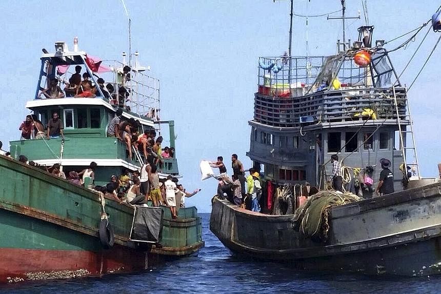 Ethnic Muslim Rohingya migrants, believed to have come from Myanmar and Bangladesh (left), receive aid supplies from a Thai fishing boat in the Andaman Sea close to Malaysia and southern Thailand on May 14,&nbsp;2015. Malaysia's foreign minister urge