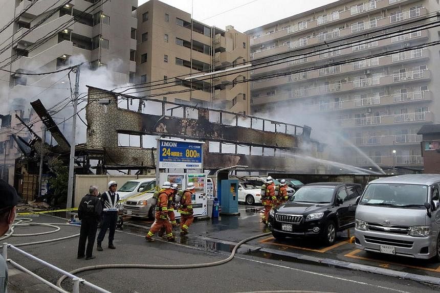 Firefighters spray water on a day-laborer's lodging house in Kawasaki, Kanagawa prefecture in suburban Tokyo on May 17, 2015. At least four people were killed in a fire early Sunday at two adjacent hostels in Kawasaki, south-west of Tokyo, while 19 o