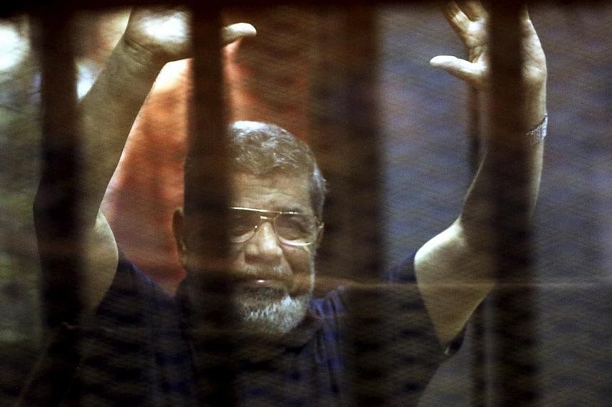Former Egyptian President Mohamed Mursi reacts behind bars with other Muslim Brotherhood members at a court in the outskirts of Cairo, Egypt on May 16, 2015. &nbsp;-- PHOTO: REUTERS