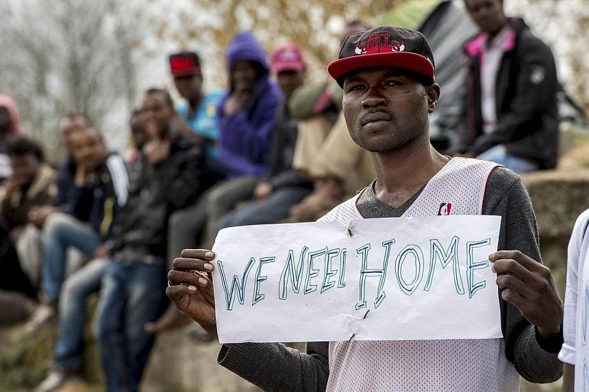 A migrant holds a sign reading "We need a home" during a visit by the French interior minister to their shelter in Calais, northern France, on May 4, 2015. -- PHOTO: AFP