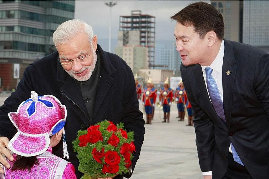 Mongolian Prime Minister Chimed Saikhanbileg (right) looks on as India's Prime Minister Narendra Modi receives a bouquet of flowers from a Mongolian child during a welcoming ceremony at the Chinggis Square in Ulan Bator on May 17, 2015. Mr&nbsp;Modi 