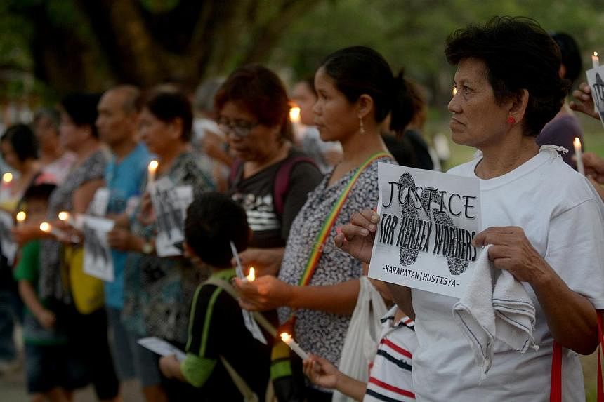 Activists hold candles and placards during a rally in Manila on May 16, 2015 for the victims of a fire that gutted a footwear factory on May 13.&nbsp;Philippine officials called on Sunday, May 17, for criminal penalties for factory owners who violate