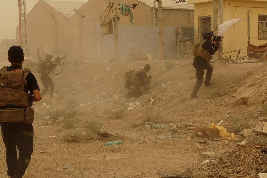 Iraqi security forces defend their headquarters against attacks by ISIS extremists in the eastern part of Ramadi in Anbar province on Thursday. ISIS militants raised their black flag over the provincial government compound in the city of Ramadi in we