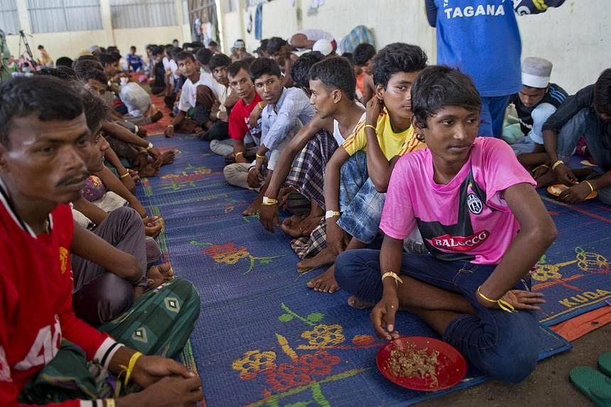 Rohingya migrants from Myanmar wait for their meal from Indonesian volunteers at the confinement area in the fishing port of Kuala Langsa in Aceh province on May 18, 2015. Myanmar acknowledged on Monday that the international community had “concern