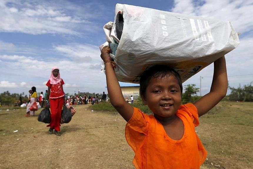 A Rohingya migrant child, who arrived in Indonesia by boat, carrying belongings while walking to a bigger shelter inside a temporary compound for refugees in Kuala Cangkoi village in Lhoksukon, Indonesia's Aceh province, on May 18, 2015. -- PHOTO: RE