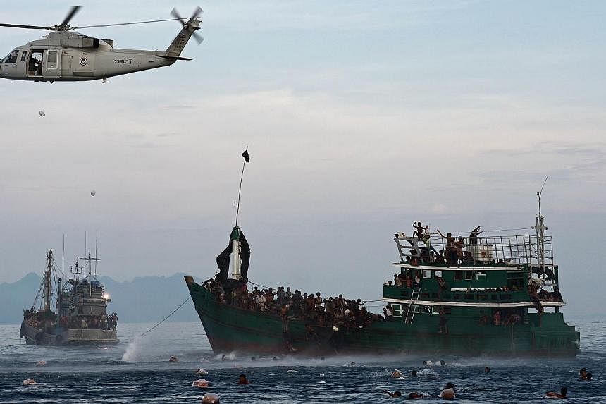 This file photo taken on May 14, 2015, shows Rohingya migrants swimming to collect food supplies dropped by a Thai army helicopter after they jumped from a boat (right) drifting in Thai waters off the southern island of Koh Lipe in the Andaman sea. -