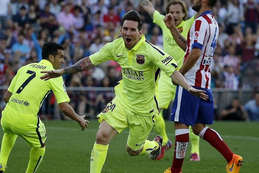 Barcelona's Lionel Messi (centre) celebrates his goal against Atletico Madrid during their Spanish first division soccer match at Vicente Calderon stadium in Madrid, Spain on Sunday. -- PHOTO: REUTERS