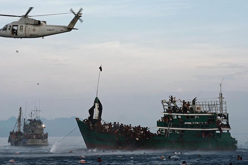 Rohingya migrants swimming to collect food supplies dropped by a Thai army helicopter after they jumped from a boat (right) drifting in Thai waters off the southern island of Koh Lipe in the Andaman sea on May 14, 2015.&nbsp; -- PHOTO: AFP