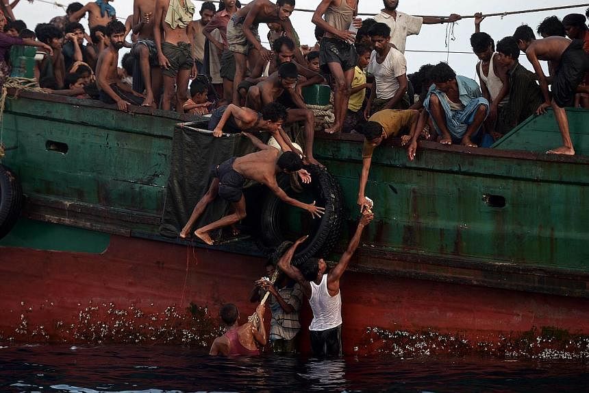 Rohingya migrants passing food supplies dropped by a Thai army helicopter to others aboard a boat drifting in Thai waters off the southern island of Koh Lipe in the Andaman sea on May 14, 2015. -- PHOTO: AFP