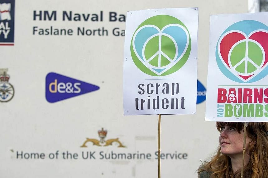 A protester calling for an end to the Trident nuclear programme holds placards at a blockade in the road in front of HM Naval Base Clyde in Faslane, Scotland, north- east of Glasgow, on April 13, 2015.&nbsp;A junior British serviceman who published a