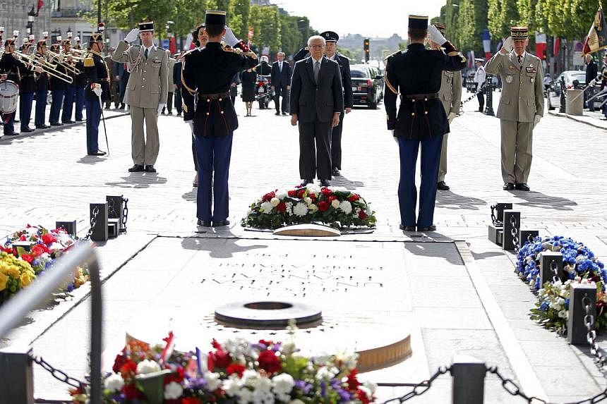 Singapore's President Tony Tan Keng Yam (centre) lays a wreath on the tomb of the unknown soldier, at the Arc de Triomphe in Paris, France, on May 19, 2015. -- PHOTO: REUTERS&nbsp;