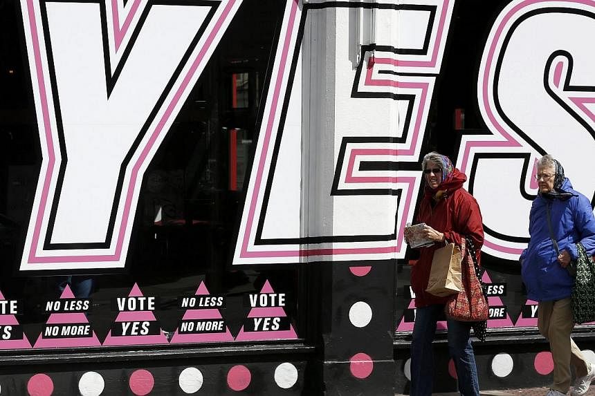 People walk past posters supporting the Yes vote, in the Caple Street area of Dublin in Ireland on Monday. Irish voters are set to back the introduction of gay marriage by a margin of as much as two-to-one and become the first country to approve the 