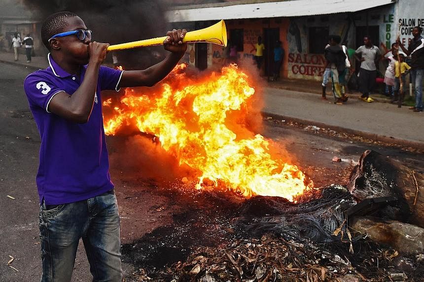 Protestors opposed to the Burundian president Pierre Nkurunziza's third term in office gather by a burning barricade during a demonstration in the Cibitoke neighbourhood of Bujumbura on May 19, 2015. Burundian security forces fired shots and tear gas