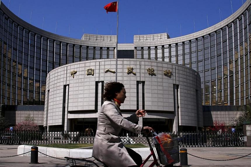 A woman riding past the headquarters of the People's Bank of China in Beijing. -- PHOTO: REUTERS