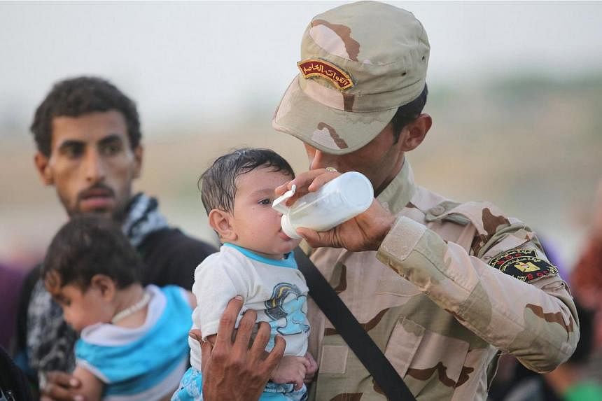 An Iraqi soldier carrying a displaced child from Ramadi on the outskirts of Baghdad on May 19, 2015. US President Barack Obama weighed faster training and arms supplies for Iraqi tribes on Tuesday, while eyeing a rapid counteroffensive to retake Rama
