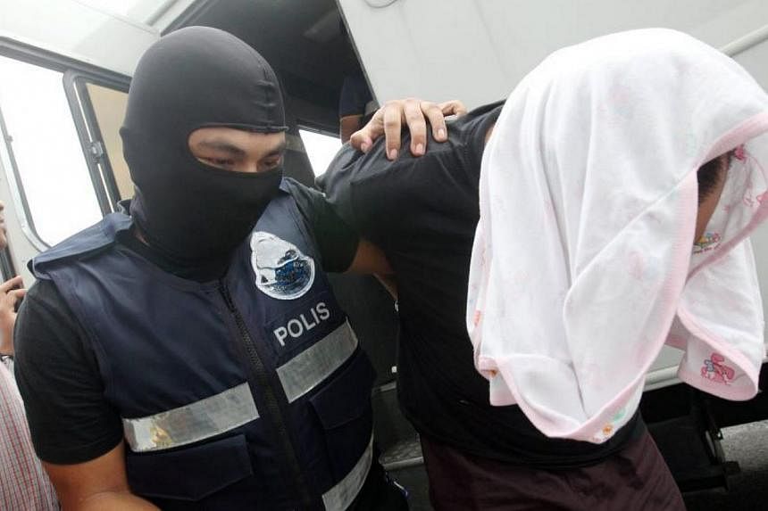 Malaysian police escorting one of six suspects arrested for being involved with terrorist activity, into Kajang court, on May 20, 2015. Five men and a teenager were charged in a Malaysian court on Wednesday with plotting terror attacks in the country