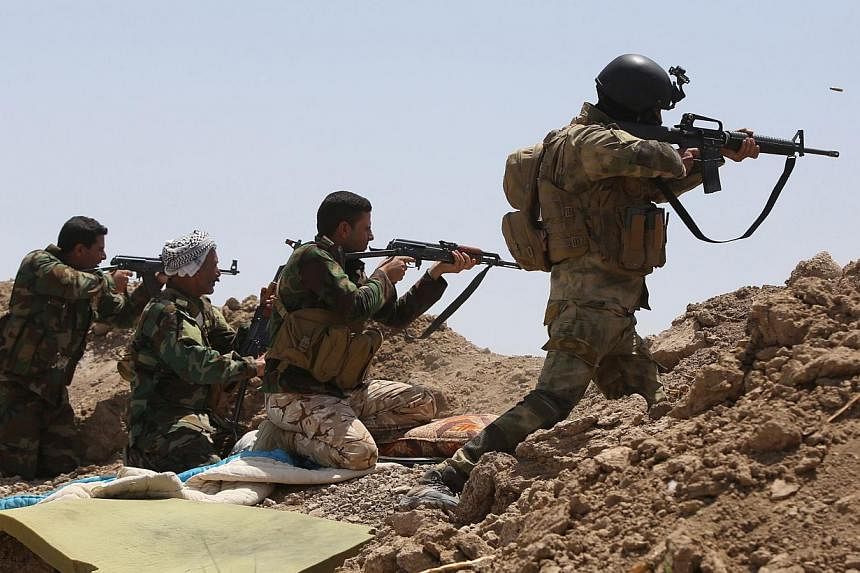 Iraqi soldiers and Shi'ite fighters from the popular committees firing towards Islamic State in Iraq and Syria (ISIS) positions in the Garma district of Anbar province west of the Iraqi capital Baghdad, on May 19, 2015.&nbsp;Iraqi forces thwarted an 
