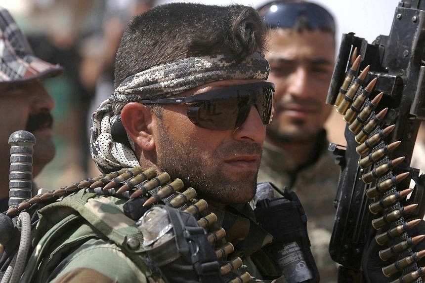 An Iraqi fighter from the Shiite Muslim Al-Abbas popular mobilisation unit holds a weapon in the area surrounding the village of Nukhayb in the embattled Anbar province west of the capital Baghdad, on Tuesday. Iraq's army and allied paramilitary forc