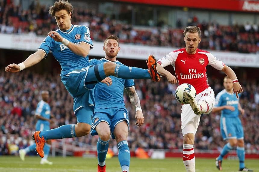 Sunderland defender Sebastian Coates (left) attempts to win the ball from Arsenal midfielder Aaron Ramsey (right) in their 0-0 draw at the Emirates Stadium in London. -- PHOTO: REUTERS&nbsp;