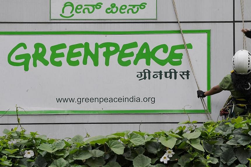 Activists of GreenPeace rappel down their office building to unfurl banners that read 'democracy' and 'freespeech' in Bangalore on May 15, 2015. Greenpeace is determined to keep operating in India even after the federal government froze its bank acco
