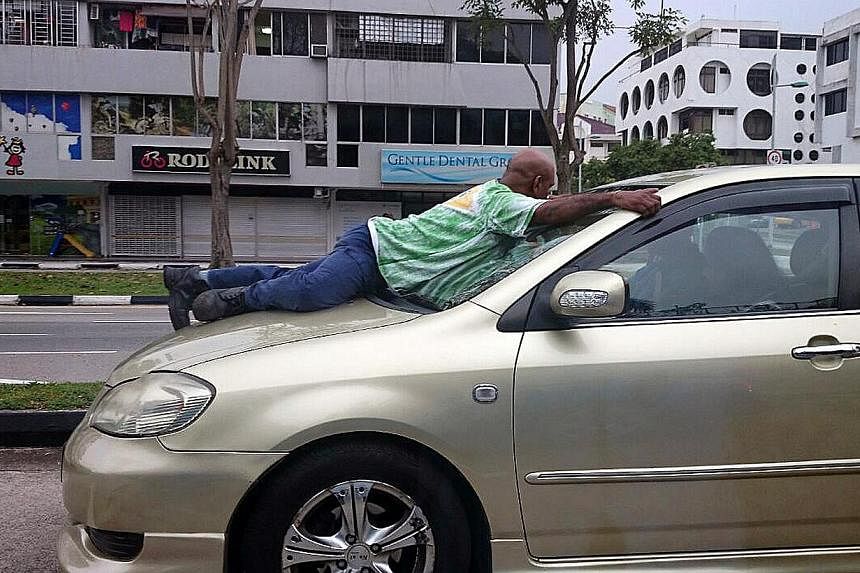 Mr Haresh Govindaraju clinging on to the windscreen of the car driven by Murali Krishnan Naidu, who was fined $2,000 and banned from the road for nine months. -- PHOTO: LIANHE ZAOBAO