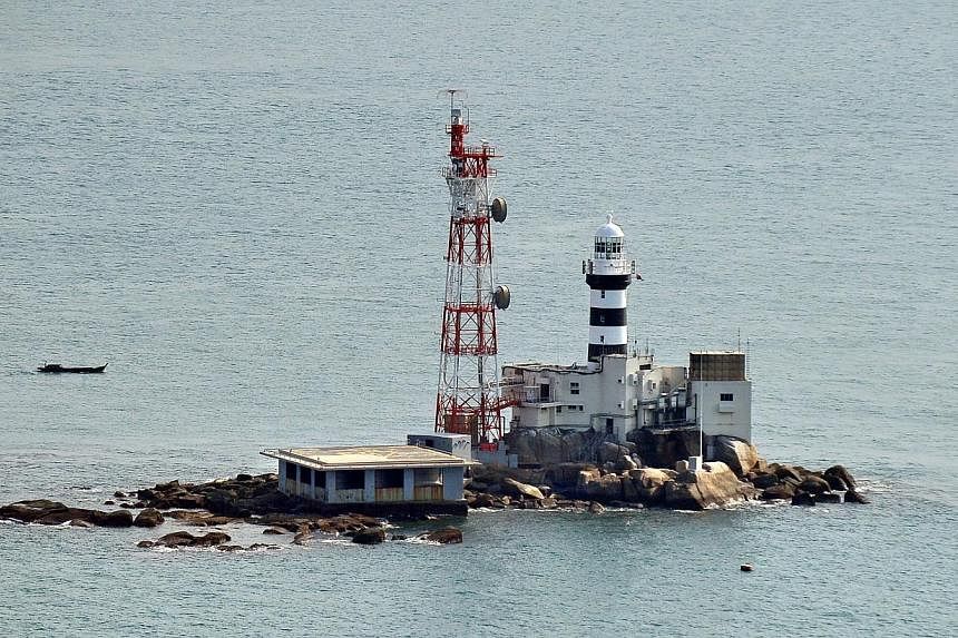 A barge that capsized with 15 crew on board in waters near Pedra Branca lighthouse (pictured) was towed to shore on Thursday, May 21, 2015, even as the search for missing crew members continues.&nbsp; -- PHOTO: ST FILE
