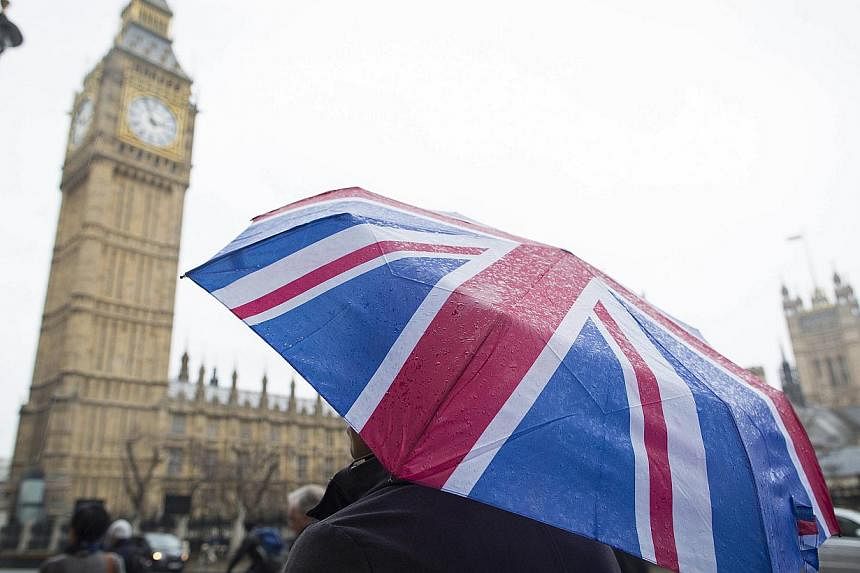 A tourist sheltering from the rain beneath a Union flag-themed umbrella, near the Houses of Parliament and the Elizabeth Tower in London on Jan 12, 2015. London received a record number of foreign visitors in 2014, with 17.4 million tourists flooding