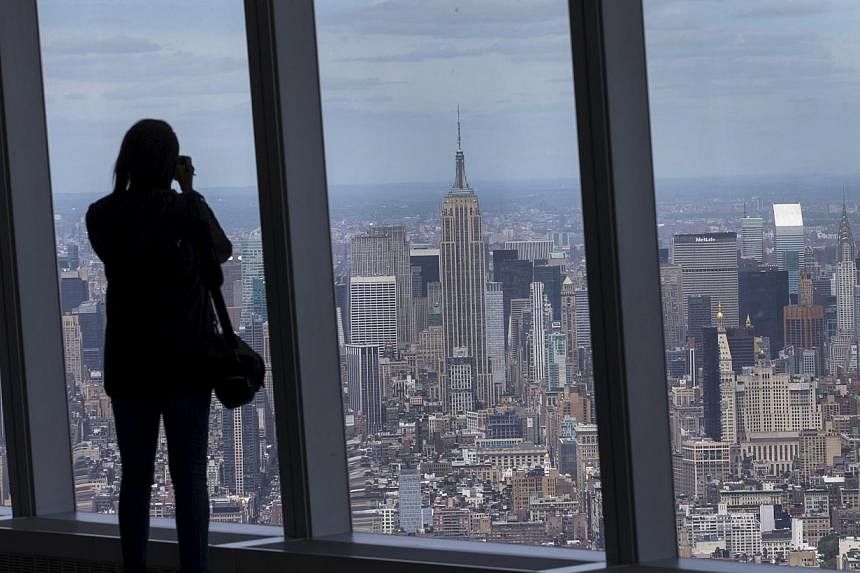 A woman photographs the Manhattan skyline from the One World Observatory on the 100th floor of the One World Trade center tower in New York during a press tour of the site May 20, 2015. One World Observatory will open to the public on May 29. -- PHOT