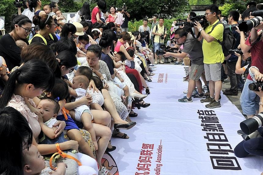 People take pictures and video as women breastfeed their children during an event to promote breast feeding in Fuzhou, Fujian province, China on May 16, 2015. Breastfeeding children for at least half a year can reduce their risk of obesity by 20 per 