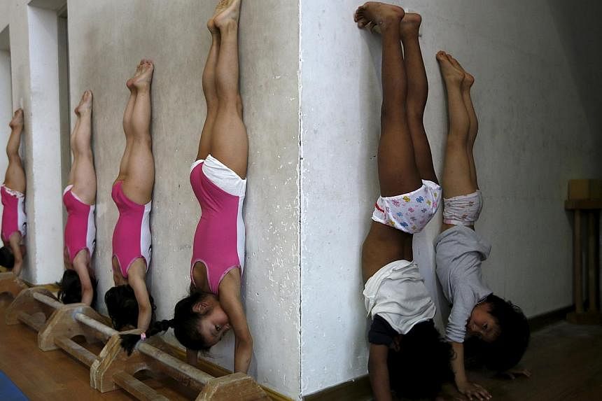 Students practice at the gymnastics hall of a sports school in Jiaxing, Zhejiang province, on May 20, 2015. Young gymnasts, from 6 to 11-year-old, train everyday for at least 5-hours. -- PHOTO: REUTERS