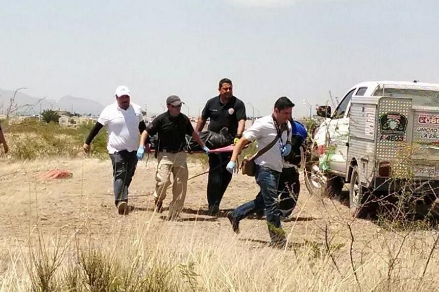 Mexican forensics carrying the dead body of a six-year old child, who was killed by minors, in Chihuahua state, Mexico, on May 19, 2015. -- PHOTO: EPA