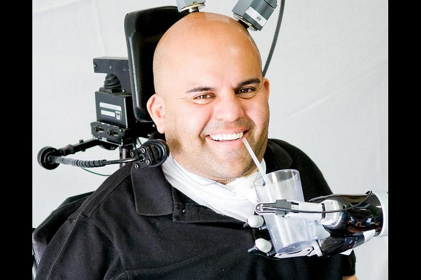 Erik Sorto, 34, who was paralysed from the neck down at age 21 after a gunshot wound, can now make a hand-shaking gesture, grab a cup to drink from and even play "rock, paper, scissors" with his robotic arm. -- PHOTO: REUTERS