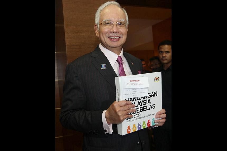 Mr Najib Razak with the 11th Malaysia Plan after tabling it in Parliament. The aim is "to break the country out of 'business as usual' practices and set Malaysia on an accelerated growth trajectory", he says.