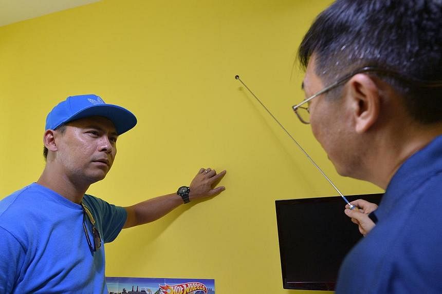 Security officer Mohamad Rizan Mazlan pointing out cracks on a wall in his Waterway Banks flat to a professional home inspector. Other residents in the estate say they have spotted cracks on their walls too.