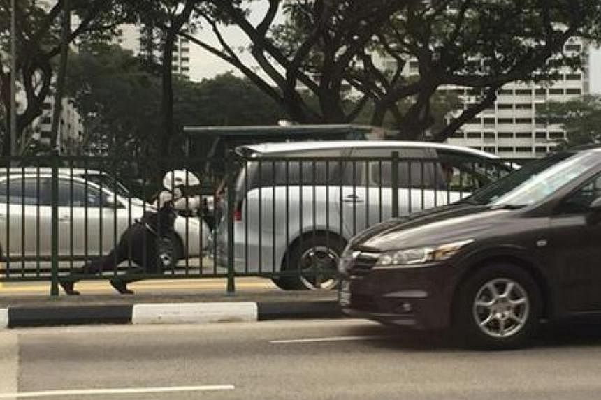 A Traffic Police officer seen pushing a car on a busy road is attracting online accolades for his "superhero" feat. -- PHOTO: SINGAPORE AUTOMOBILE.COM/FACEBOOK