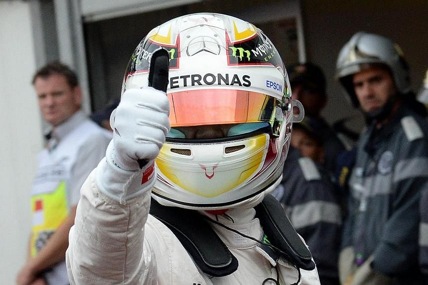 Mercedes AMG Petronas F1 Team's British driver Lewis Hamilton (R) gives the thumbs up as he celebrates taking the pole position in the pits after after the qualifying session at the Monaco street circuit in Monte-Carlo on May 23, 2015. -- PHOTO: AFP