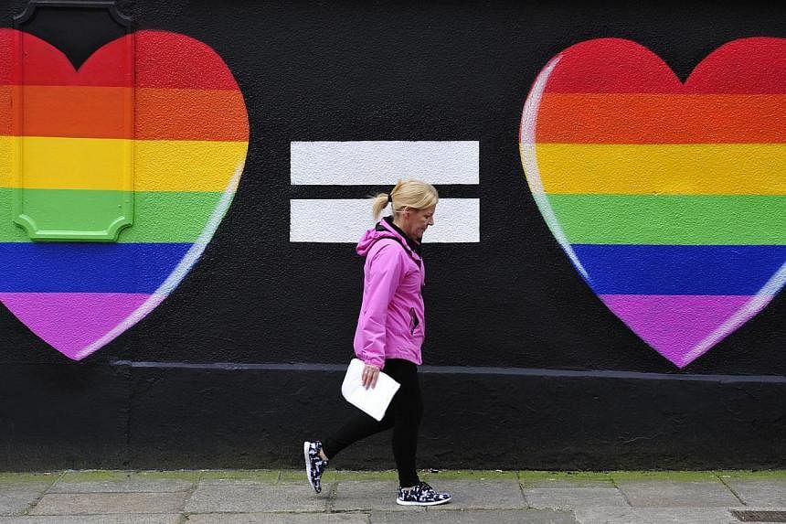 A woman walking past a mural of two hearts painted in rainbow colours in Dublin on May 22, 2015. -- PHOTO: EPA