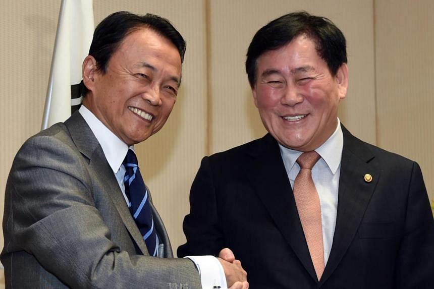 Japanese Finance Minister Taro Aso (left) welcoming his South Korean counterpart Choi Kyung Hwan during a South Korea-Japan finance ministers' dialogue meeting in Tokyo on May 23, 2015. -- PHOTO: AFP&nbsp;