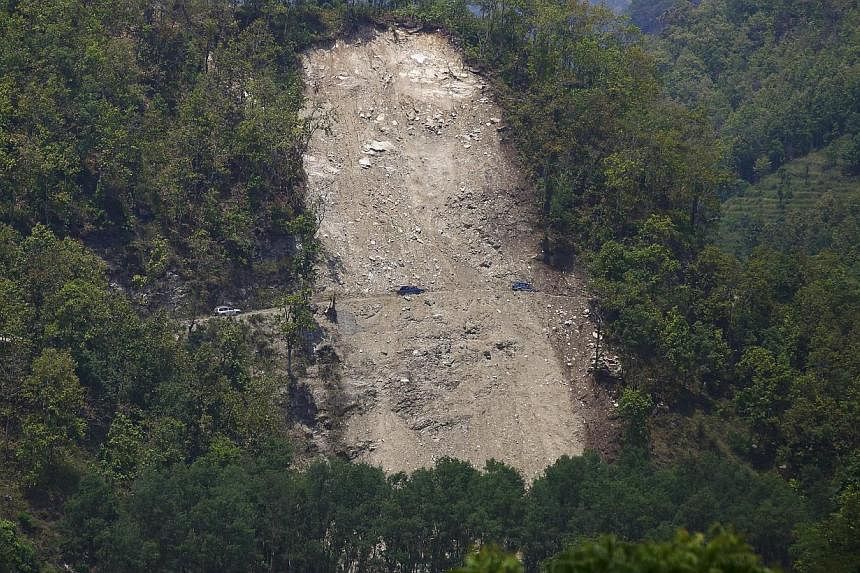 Vehicles pass by a landslide after the earthquake in the Gorkha district of Nepal on May 20, 2015. A landslide in the Myagdi district on Sunday, May 24, sent mud and rocks surging into the Kali Gandaki river, causing thousands of panic-stricken villa