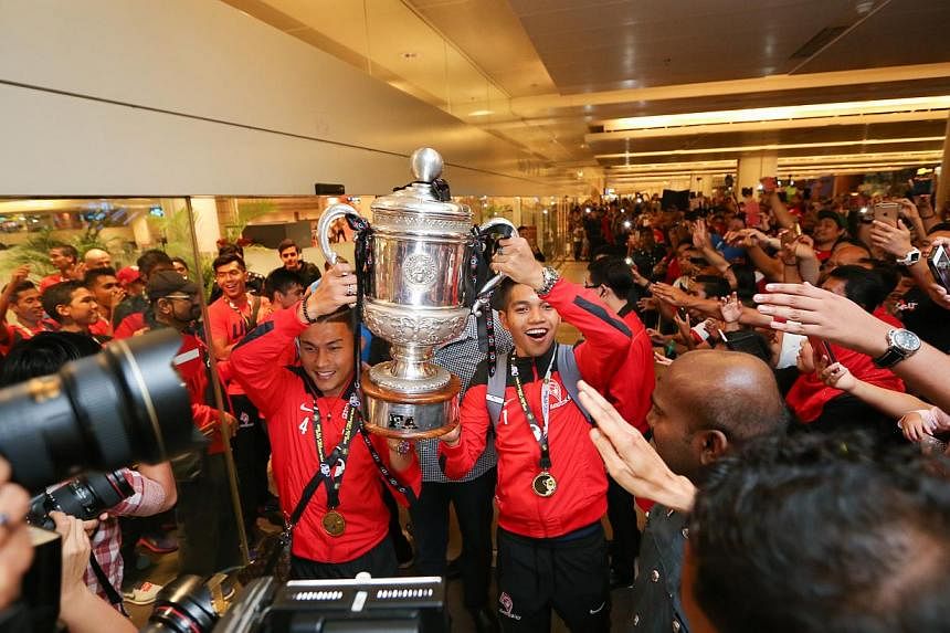LionsXII captain Isa Halim and vice-captain Izwan Mahbud holding the Malaysian FA Cup trophy as the team enters the arrival hall of Changi Airport Terminal 2 on Sunday evening. -- ST PHOTO: ONG WEE JIN&nbsp;