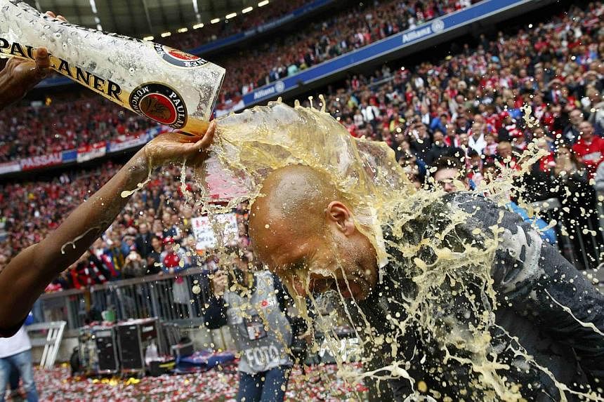 Bayern Munich's David Alaba (left) pours beer over coach Pep Guardiola after their final Bundesliga match of the season against Mainz on May 23, 2015. -- PHOTO: REUTERS