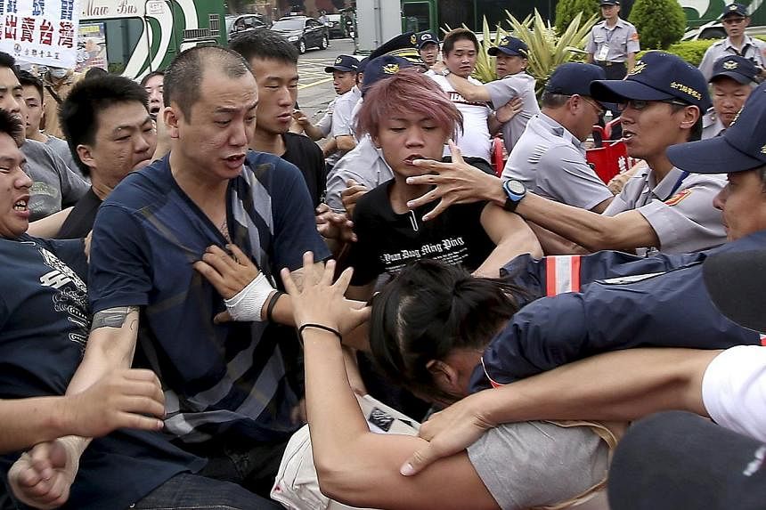 Pro-China activists (left in black shirts) fight with a pro-Taiwan activist (right in yellow vest) as police officers attempt to stop them in Kinmen, Taiwan's offshore island, on May 23, 2015. -- PHOTO: REUTERS