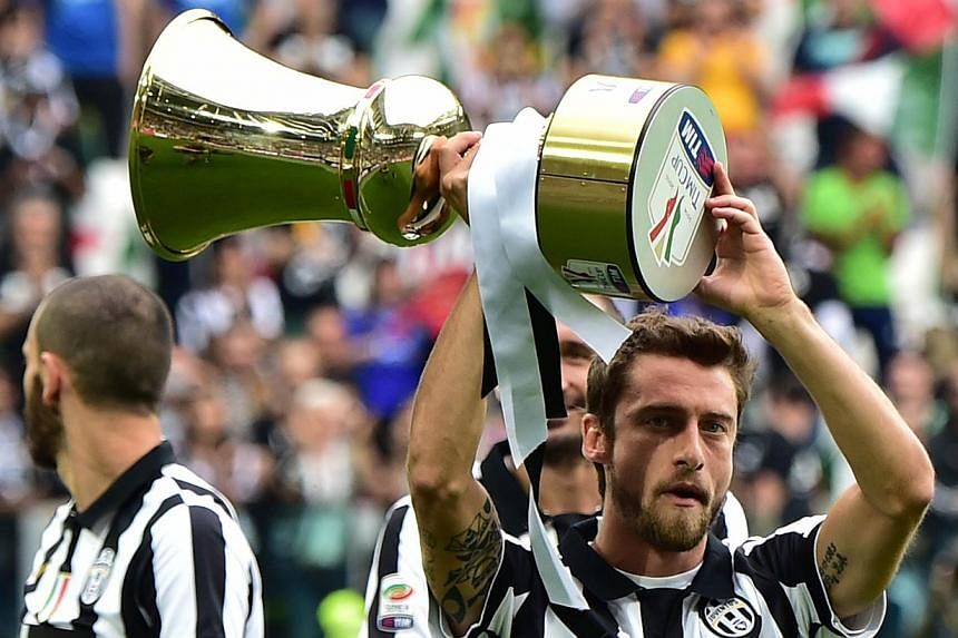 Juventus midfielder Claudio Marchisio holds the Cup as players present the Tim Cup trophy (Coppa Italia) to their fans prior their Serie A match against Napoli on May 23, 2015 at the Juventus stadium in Turin. Juventus won the Coppa Italia final matc
