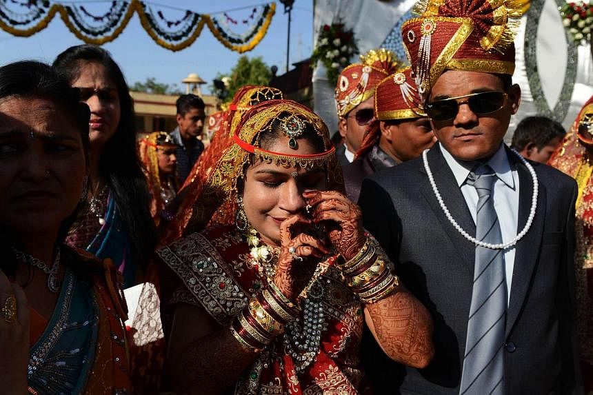 An Indian bride (centre) adjusts her jewellry ahead of a mass wedding in Ahmedabad on May 17, 2015. -- PHOTO: AFP