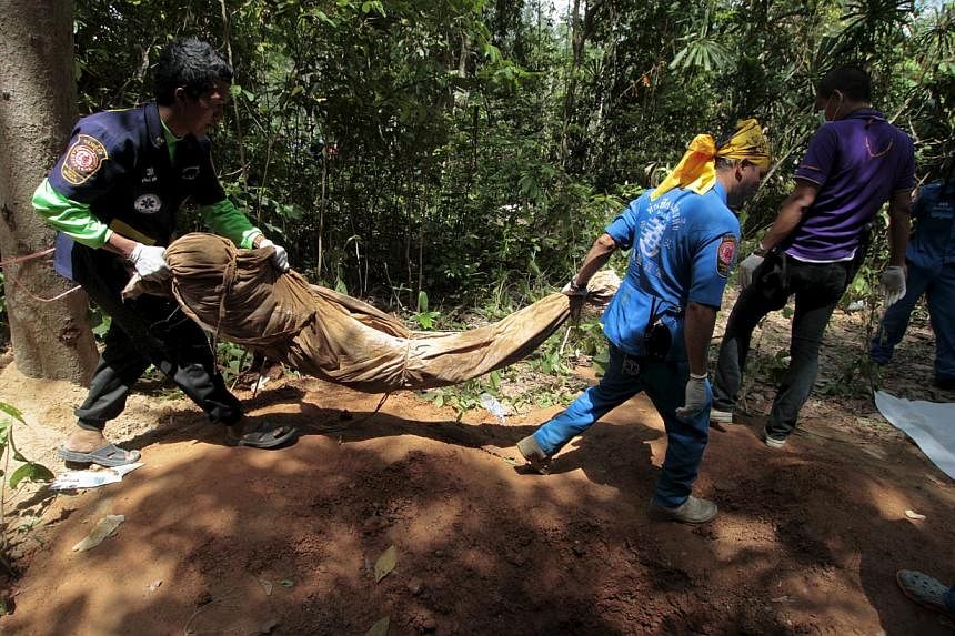 Rescue workers carry a body bag with remains retrieved from a mass grave at a rubber plantation near a mountain in Thailand's southern Songkhla province on May 6, 2015. Malaysian Prime Minister Najib Razak said on Monday that Malaysia will find those