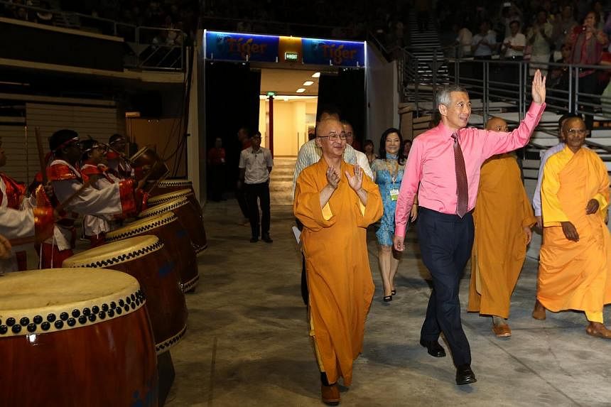 Prime Minister Lee Hsien Loong acknowledging the crowd as he enters the Singapore Indoor Stadium with Venerable Seck Kwang Phing (left), president of the Singapore Buddhist Federation (SBF), for a Vesak Day and SG50 concert organised by the Singapore