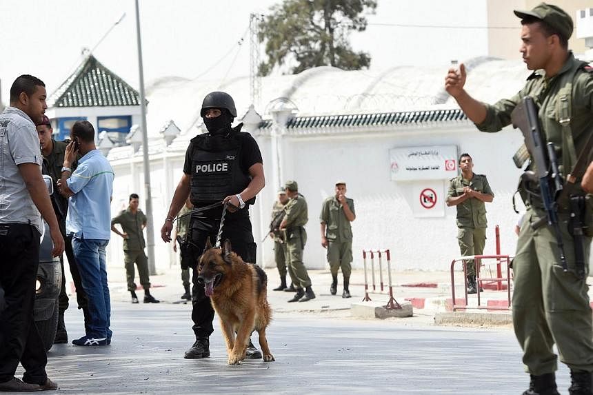 Tunisian soldiers and policemen stand guard outside the Bouchoucha army barracks in Tunis on May 25, 2015 after a soldier opened fire at his colleagues. -- PHOTO: AFP