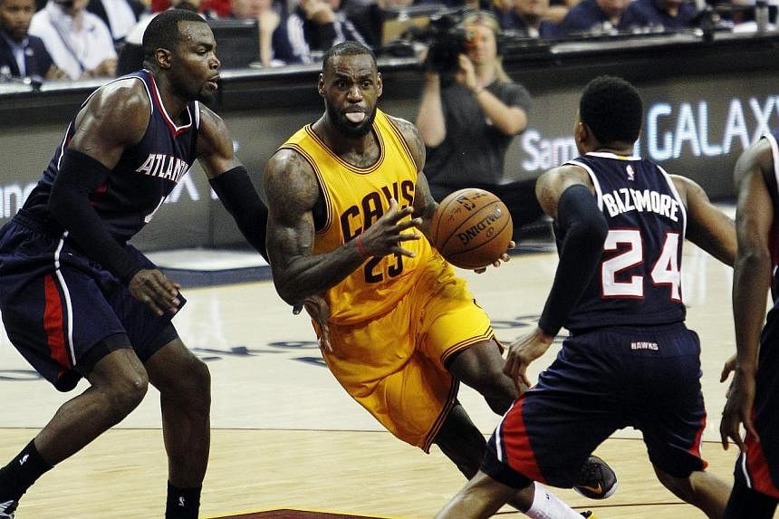 LeBron James (centre) of the Cleveland Cavaliers drives to the basket against (from left) Paul Millsap, Kent Bazemore, and DeMarre Carroll of the Atlanta Hawks during the second half of their NBA Eastern Conference Finals game 3 at Quicken Loans Aren